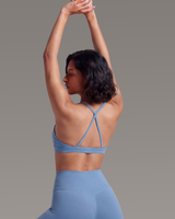 Woman wearing a blue sports bra and leggings against a gray background