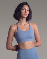 Woman wearing a blue sports bra and leggings against a gray background