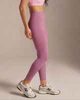 Woman wearing a pink sports bra and leggings against a beige background