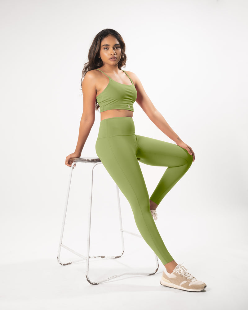 Model posing in a green sports bra and matching leggings, showcasing the coordinated activewear set that is suitable for workout and daily wear