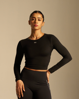 Woman wearing a black long-sleeve top and leggings on a beige background