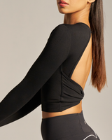 Woman wearing a black long-sleeve crop top and leggings on a neutral background