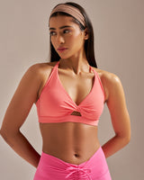Woman wearing a pink sports bra and leggings against a beige background