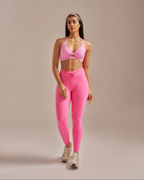 Woman wearing a pink sports bra and leggings set on a beige background