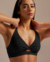 Woman wearing a black sports bra with a neutral background