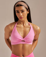 Woman wearing a pink sports bra and shorts on a beige background