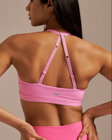 Woman wearing a pink sports bra and leggings against a neutral background