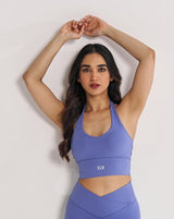 female model in periwinkle blue halter neck sports bra suitable for variety of athletic activities, gym, yoga and workout.