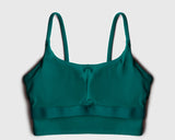 Flatlay of a teal green sports bra showing internal structure of built-in bra pads 
