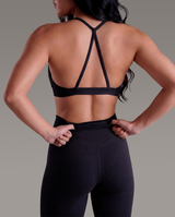 Person wearing a black sports bra and leggings on a gray background