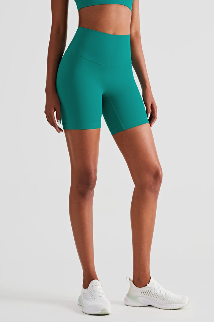 athletic female model posing in premium green high waisted shorts that is squat proof and perfect for yoga, running, dancing, gym and athletic activities