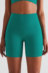 athletic female model posing in premium green high waisted shorts that is squat proof and perfect for yoga, running, dancing, gym and athletic activities