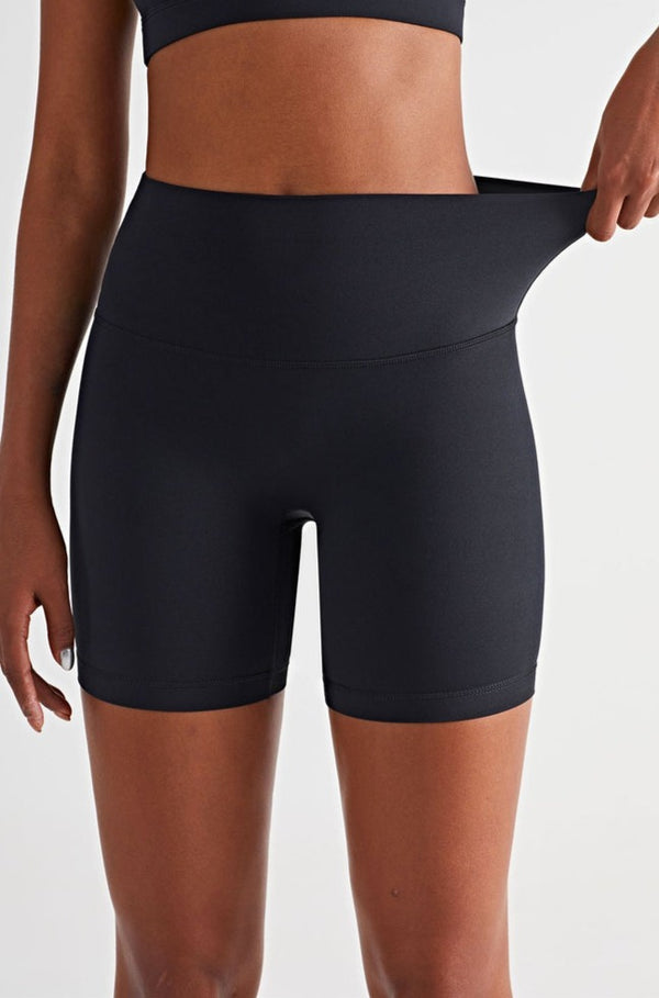 athletic model posing in premium black high waisted and squat proof bike shorts showing stretchability of shorts