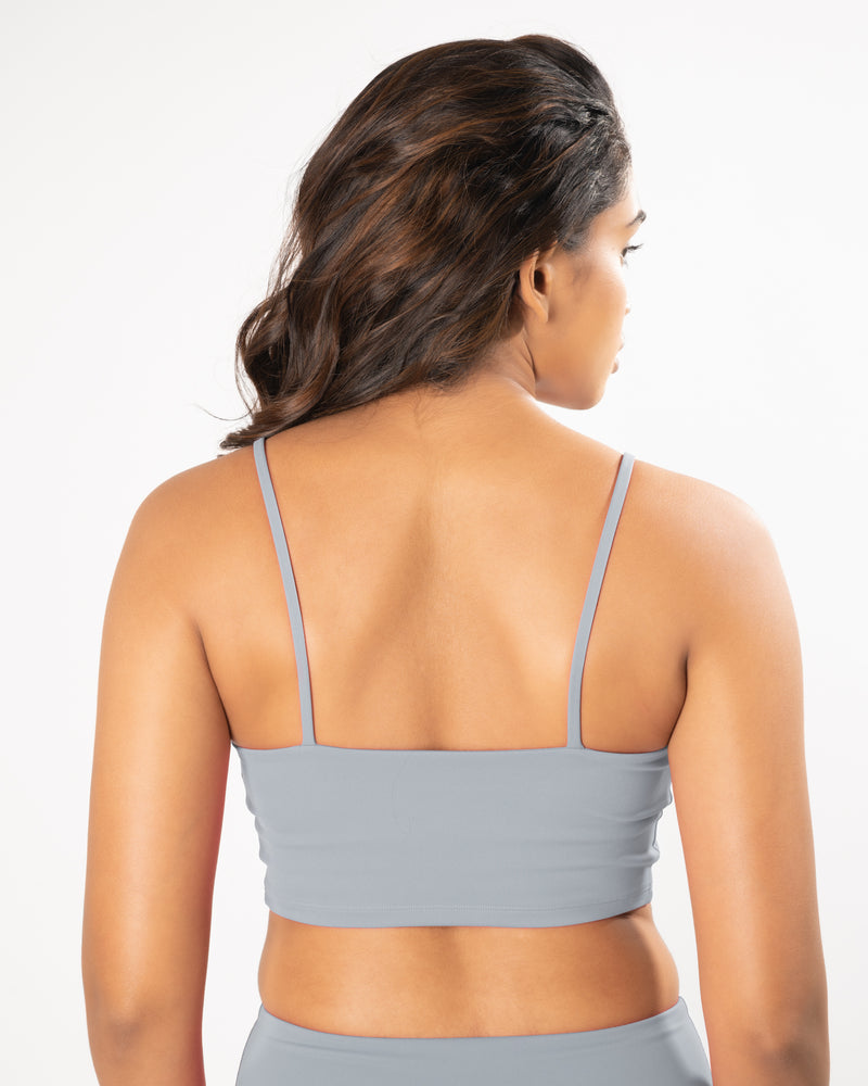 Model wearing and showing back of a grey sports bra, suitable for high impact workout activities.
