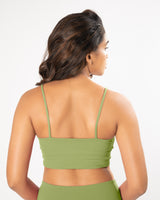Female model wearing and showing back structure of a matcha green sports bra, suitable for a variety of workout activities.