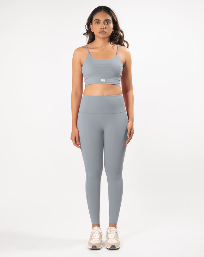 Female model posing in a grey sports bra and leggings, showcasing the coordinated activewear set that is suitable for gym and yoga