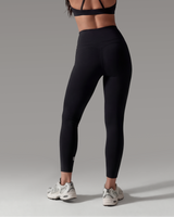 Person wearing a black sports bra and leggings on a gray background