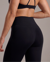 Person wearing a black strappy top and leggings against a neutral background