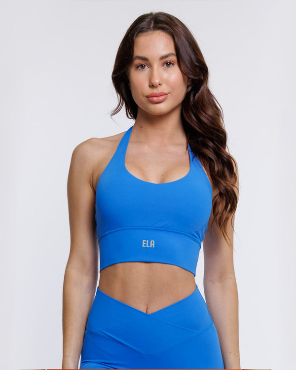 Athletic woman in electric blue halter neck sports bra suitable for variety of athletic activities, gym, yoga and workout.