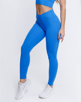 An athletic female model wearing the ButterBod Hourglass Leggings in colour electric blue, highlighting close up of legging. The high-waisted wrap design and V-cut waistband accentuate her curves, while the booty-lifting back seam provides a flattering lift. The legging has a soft matte finish, medium compression, and is made from 4-way stretch fabric for maximum comfort and versatility.