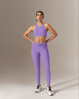 Woman wearing a purple athletic outfit standing against a neutral background