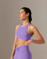 Woman wearing a purple athletic outfit standing against a neutral background