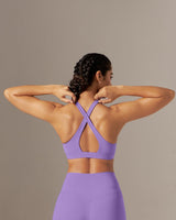 Person wearing a purple sports bra and leggings set against a neutral background