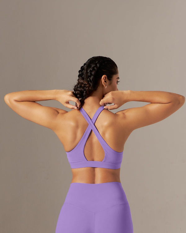 Person wearing a purple sports bra and leggings set against a neutral background