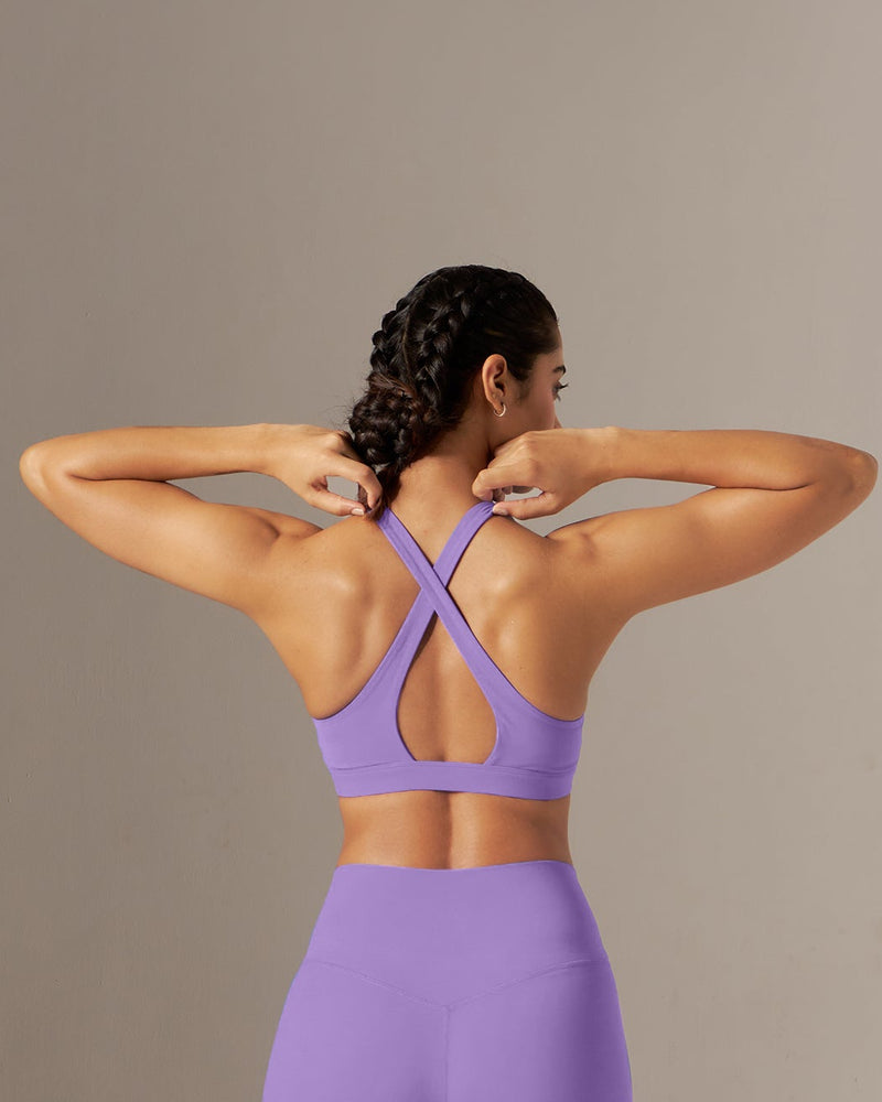 Person wearing a purple sports bra and leggings set against a neutral background
