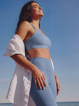 Woman in blue athletic wear standing against a clear blue sky.