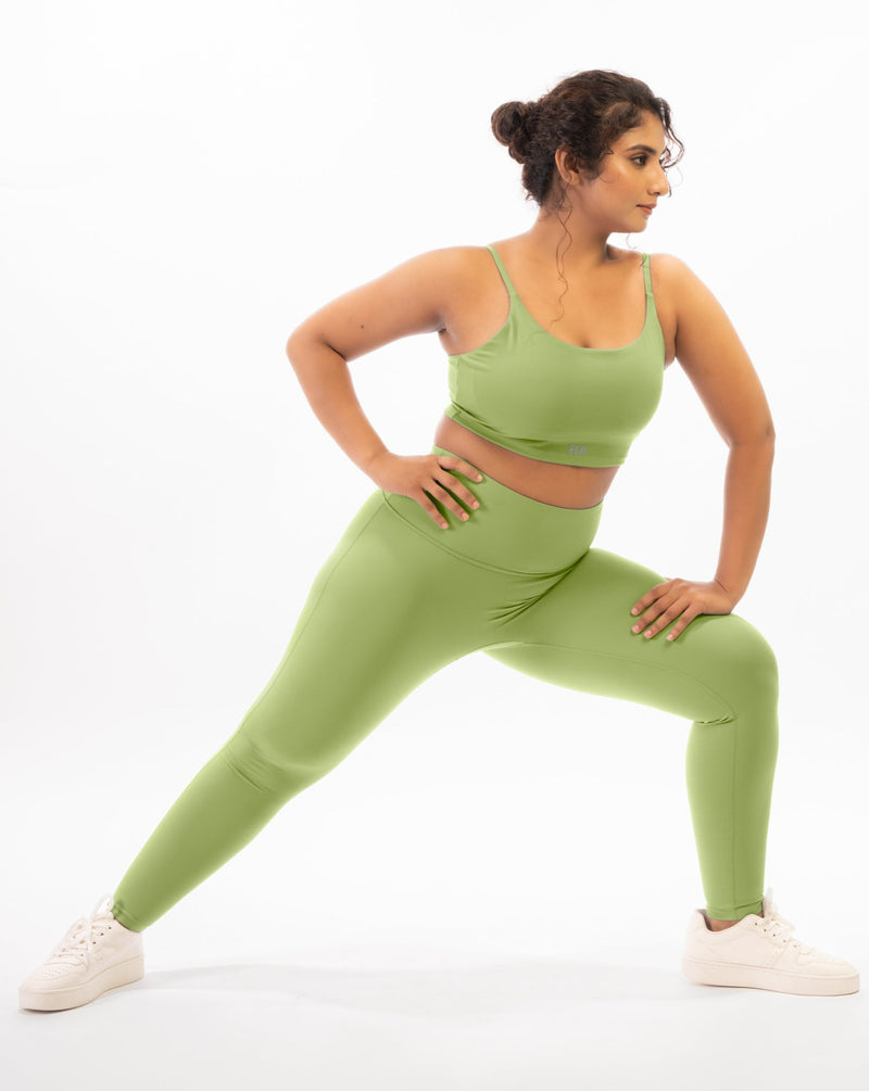 A plus size female model posing in a green sports bra and leggings, showcasing the coordinated activewear set that is suitable for gym and yoga