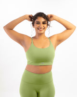 a plus size female model wearing a matcha-green sports bra, suitable for a variety of workout and athletic activities.