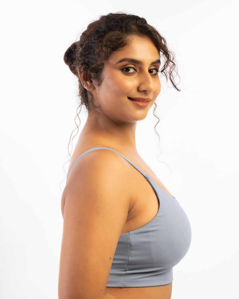 a plus size female model standing sideways wearing a grey sports bra, suitable for a variety of workout and athletic activities.