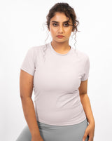 Female athlete showcasing the pale grey Performance Tee, a high-tech workout top designed to minimize distractions and provide elite-level performance during medium to high impact workouts