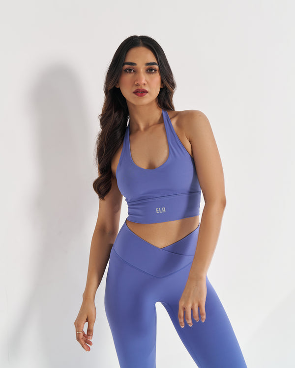 female model in periwinkle blue halter neck sports bra suitable for variety of athletic activities, gym, yoga and workout.