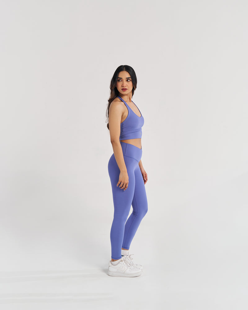 female model showing flattering back design of periwinkle blue halter neck sports bra suitable for variety of athletic activities, gym, yoga and workout.