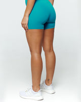 Back view of Turquoise Blue Bike shorts on a female fit model highlighting Criss Cross High Waistband and Squat-Proof features