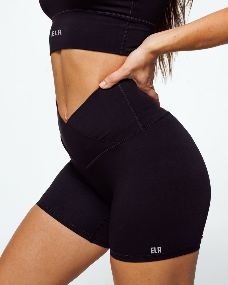 female athletic model wearing buttery smooth bike shorts perfect for running, biking and daily life. The high waistband shows the criss cross feature with wrapover waistline and shows squat proof feature.