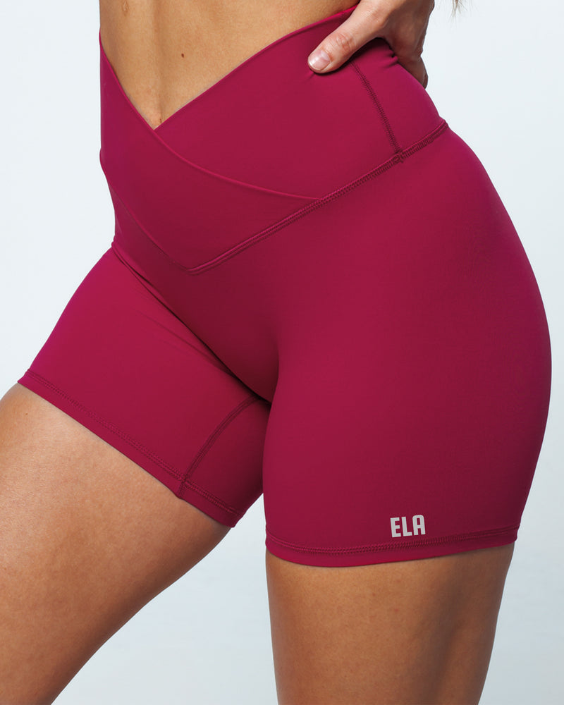 Female athletic model in Pinch-free Criss Cross High Waistband, Anti-Camel Toe, Seam-Free Front Panel, Slimming & Buttery-Smooth, Squat-Proof Bike Shorts in magenta colour from front