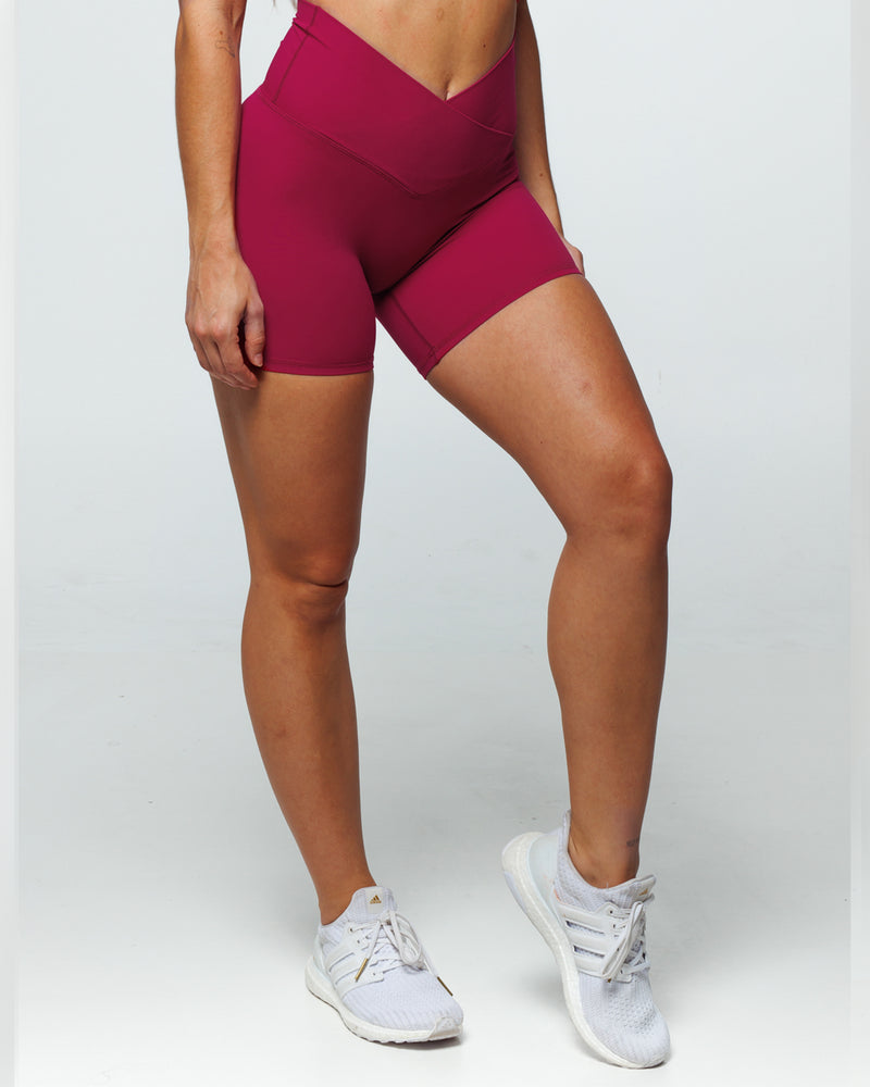Magenta Bike shorts on a female fit model highlighting Pinch-free Criss Cross High Waistband, Anti-Camel Toe, Seam-Free Front Panel, Slimming + Buttery-Smooth, and Squat-Proof features