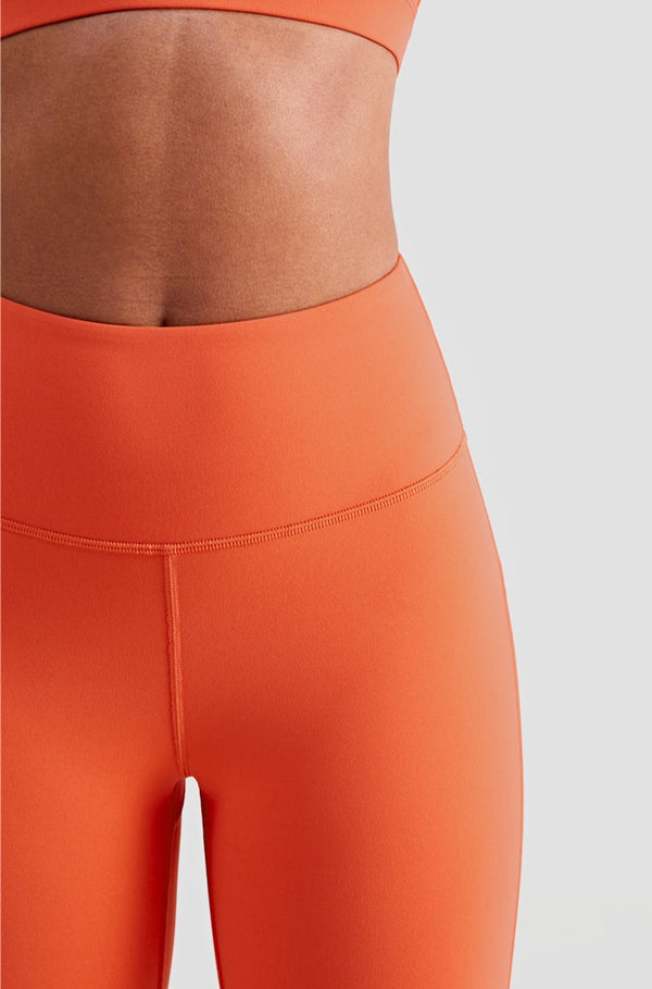 Female model posing to display Orange buttery smooth leggings with a high waist and ankle-length fit suitable for gym, yoga and other athletic activities