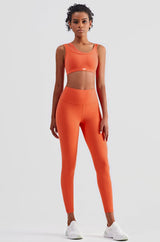 female model wearing orange sports bra with built-in padding for extra support with the matching high waisted compressive leggings. the bra is suitable for gym, yoga or any athletic activities