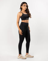 Model posing in black activewear set including a sports bra and gym leggings, perfect for any workout or athletic activity.
