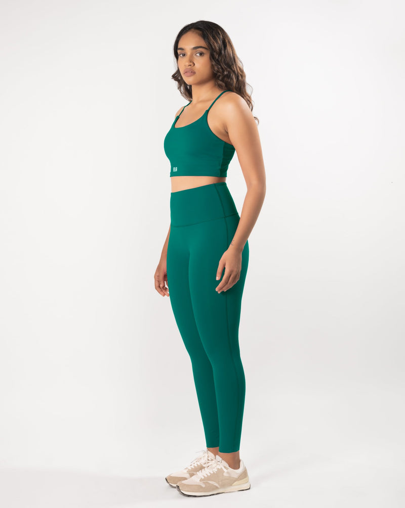Female Model posing in a teal green sports bra and matching leggings, showcasing the coordinated activewear set that is suitable for workout and daily wear