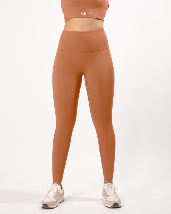 Female model posing to display beige leggings with a high waist and ankle-length fit, perfect for any athletic activity and suitable for gym, yoga and other workout activities.