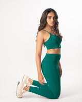 Female Model posing in teal green activewear set including a sports bra and high-wiasted gym leggings that is suitable for high impact workout
