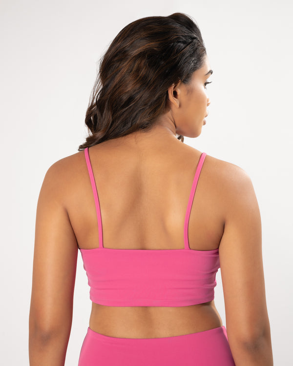 Model wearing and showing back of a pink sports bra, suitable for a variety of workout activities.