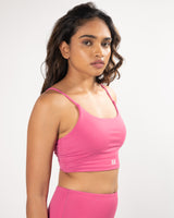 Model showing side view of a pink sports bra, suitable for a variety of workout activities.