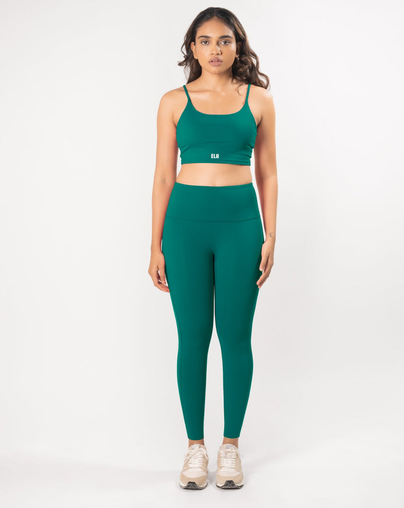 Model posing in a teal green sports bra and matching leggings, showcasing the coordinated activewear set that is suitable for workout and daily wear