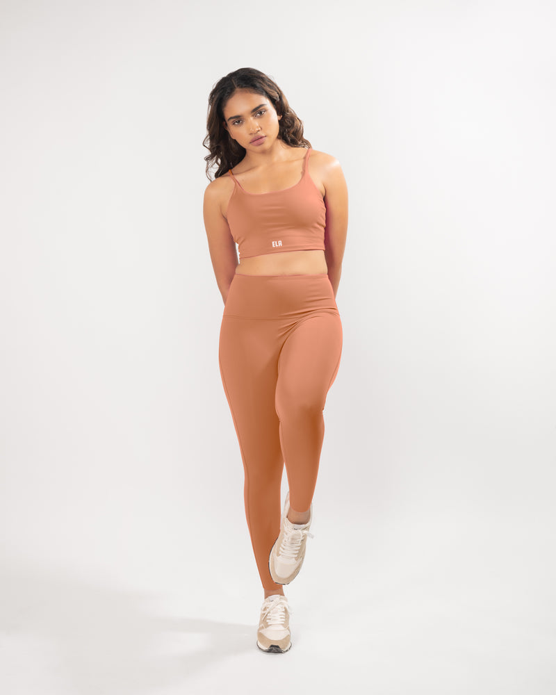 Female Model posing in beige activewear set including a sports bra and high-wiasted gym leggings that is suitable for high impact workout